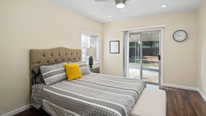 Un dormitorio con una cama grande, un ventilador de techo y un puerta corrediza de vidrio que da a un patio.