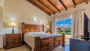 Une chambre à coucher avec un lit en bois, deux tables de chevet avec des lampes, une commode et une grande fenêtre avec des rideaux.