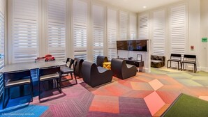 A modern conference room with a large TV, comfortable seating, and a colorful geometric carpet. - 8967ameila (Kissimmee)