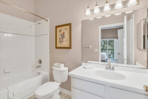 A modern bathroom with a bathtub, toilet, and vanity with a large mirror. - 611 Lucaya (Davenport)