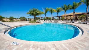 A circular pool with lounge chairs and palm trees, surrounded by a tiled deck. - 8958silver (Kissimmee)