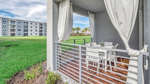 A balcony with white curtains, a white table, and a white chair. - 3180paraunit101 (Kissimmee)