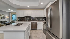 A modern kitchen with white cabinets, stainless steel appliances, and a large island. - 3180paraunit101 (Kissimmee)