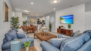 A modern living room with a sofa, coffee table, and a TV displaying a beach scene. - 8911zurich (Kissimmee)