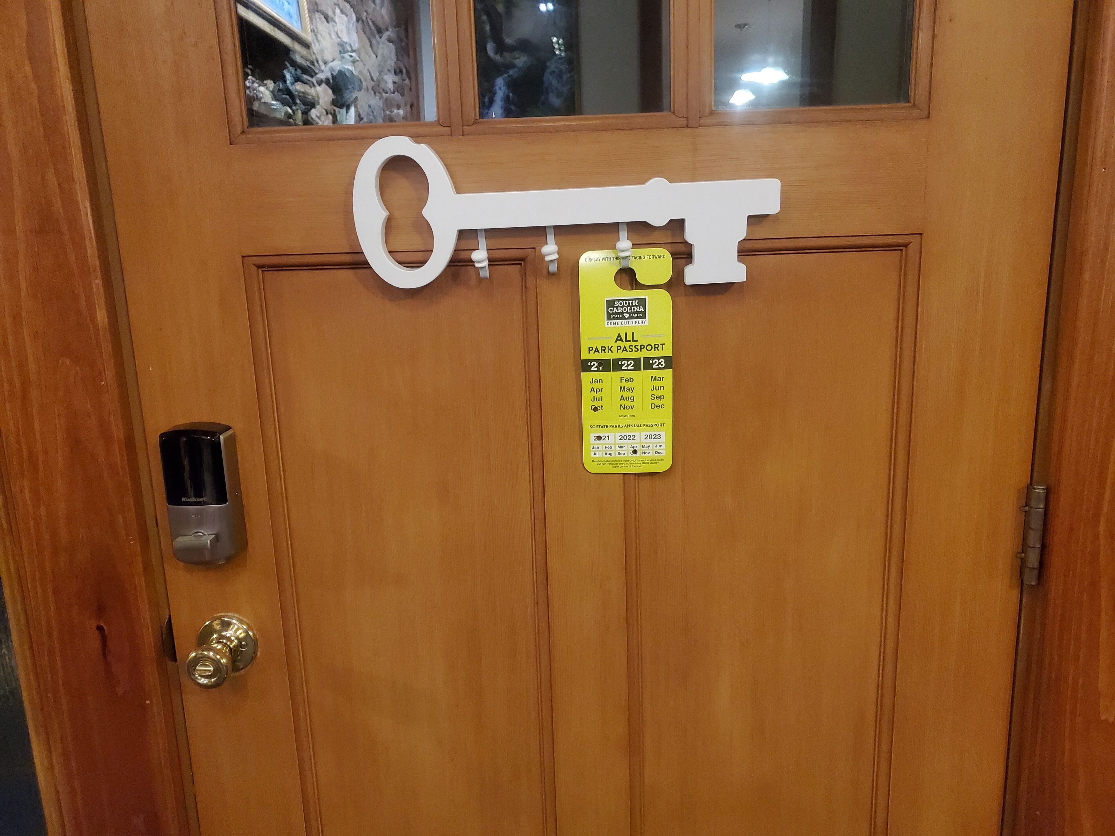Una puerta de madera con una cerradura, una placa con forma de llave y un distintivo de estacionamiento amarillo.