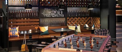 A bar area with a foosball table, seating, and a wall of liquor bottles.