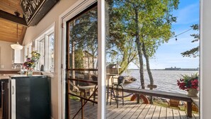 Et køkken med køleskab, et spiseområde med stole, og en terrasse med udsigt over vand.
