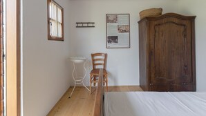 A bedroom with a wooden bed, a wooden chair, a small table, and a cabinet. - Small house "BreadLady" (Koper)
