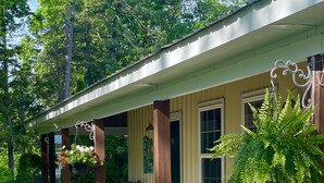 A covered porch with a concrete floor, wooden pillars, and a hanging flower basket. - Enjoy the beautiful views of the Muskegon River near Hardy Dam and Dragon Trail (Newaygo)