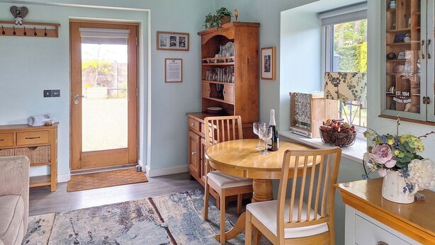 Un coin repas avec une table et des chaises en bois, une bibliothèque et une fenêtre donnant sur un paysage agréable.