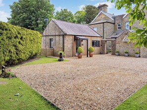 A stone building with a gravel driveway, a small wooden structure, and potted plants. - The Studio at Westfield (Bellingham, near Hexham)