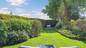 A garden with a table and chairs, a hedge, and a stone wall. - The Studio at Westfield (Bellingham, near Hexham)