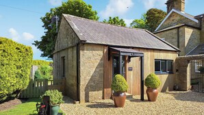 A stone building with a sloped roof, a wooden door, and two potted plants. - The Studio at Westfield (Bellingham, near Hexham)