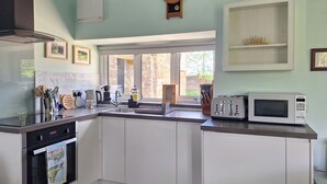 A kitchen with white cabinets, a microwave, a toaster, and a sink. - The Studio at Westfield (Bellingham, near Hexham)