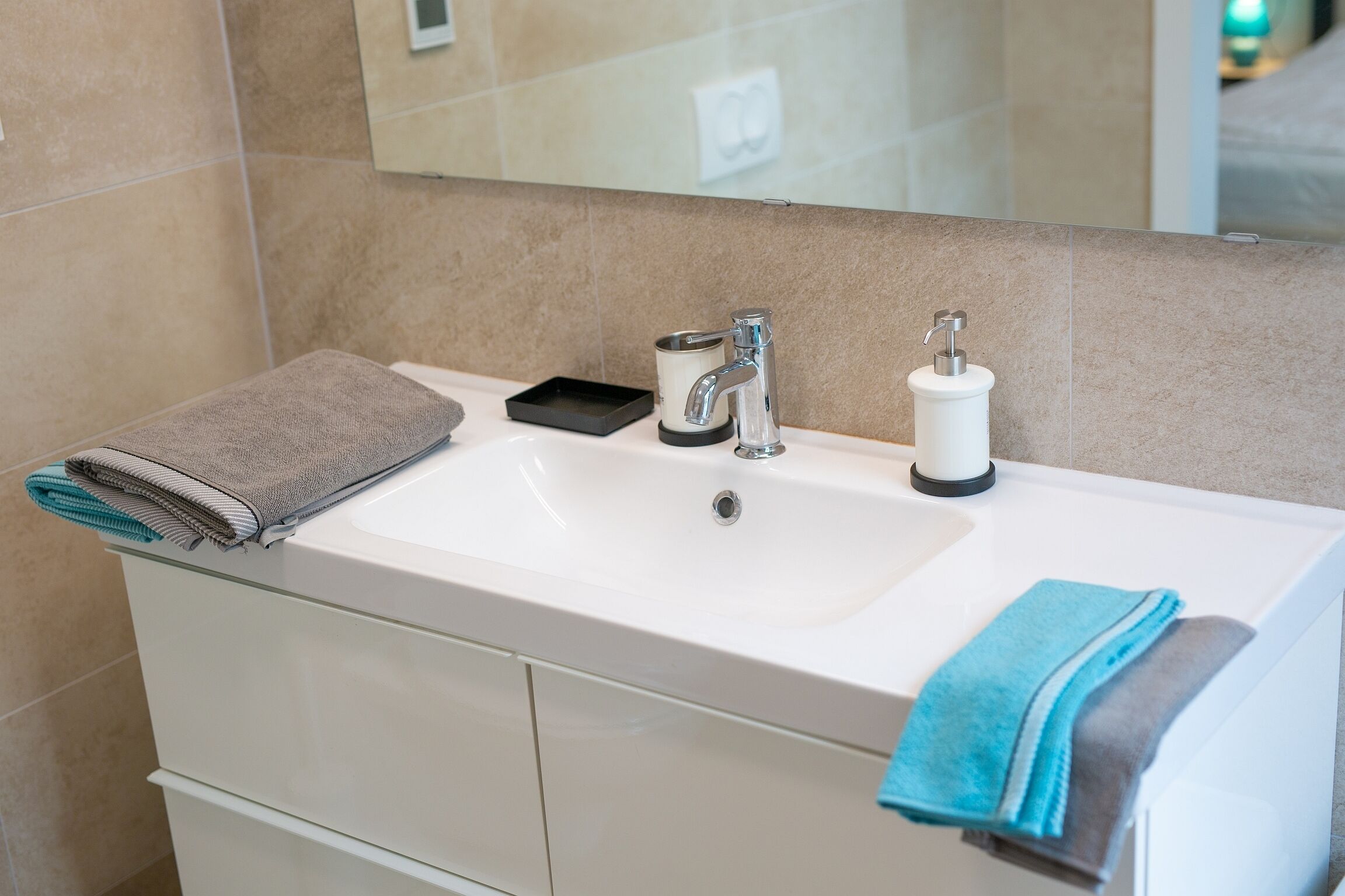 Ein Badezimmer mit einem weißen Waschbecken, einem Spiegel und einem Handtuchhalter.