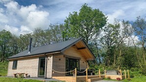 A wooden cabin with a sloped roof, a chimney, and a porch with a rope barrier. - 2 bedroom accommodation in Cwrt Newydd, near Llandysul (Cwrt Newydd, near Llandysul)
