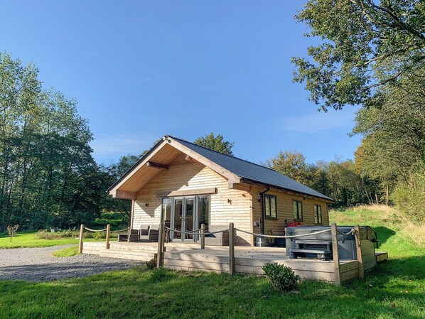 A wooden cabin with a sloped roof, a porch, and a fenced entrance.