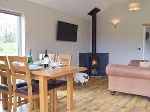 A dining area with a table set for two, a fireplace, a sofa, and a decorative sheep.