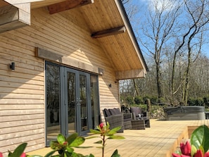A wooden cabin with a sliding glass door, outdoor seating, and a deck.