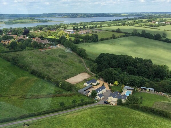 An aerial view of a residential area with houses, green fields, and a lake. - Fennel Folly - UK32608 (Manton, near Oakham)