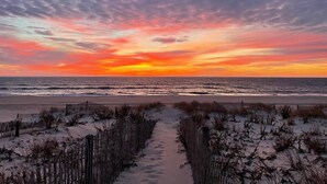 A beach path leading to the ocean with a sunset in the background.