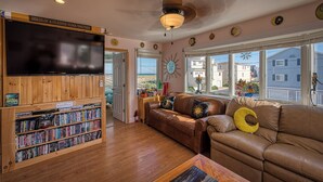 A cozy living room with a wooden bookshelf, leather sofa, and a large TV.