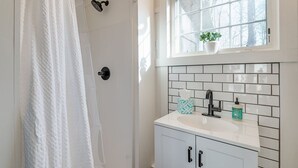 A bathroom with a white shower curtain, a window with a plant, a sink with a soap dispenser, and a tiled backsplash. - 10 minutes to Asheville, Biltmore Estate, hike and bike trails (Fairview)