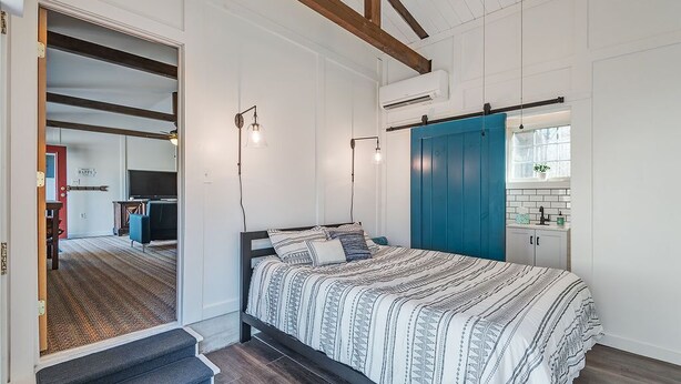 A bedroom with a bed, a blue wardrobe, a small kitchenette, and a staircase leading to another room. - 10 minutes to Asheville, Biltmore Estate, hike and bike trails (Fairview)