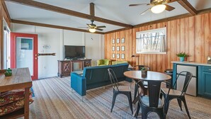 A cozy room with a wooden ceiling, a red door, a television, a sofa, a dining table with chairs, and a kitchen area. - 10 minutes to Asheville, Biltmore Estate, hike and bike trails (Fairview)