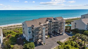 A beachfront hotel with multiple floors, balconies, and a parking area. - Maritime West Unit C-33-Ocean Front Condo (Atlantic Beach)