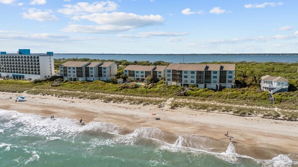 Ein Hotel direkt am Strand mit mehreren Gebäuden, einem Sandstrand und dem Meer.