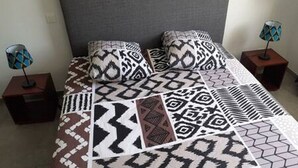 A bed with patterned bedding, two nightstands with lamps, and a grey headboard.