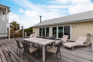 En træterrasse med et bord og stole, en overdækket patio og havudsigt.