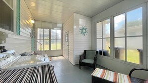 A room with a large window, a chair, a small table, and a bathtub.