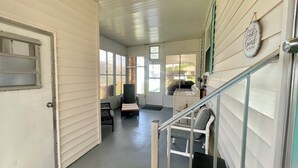 A hallway with a door, a bench, a chair, and a staircase.