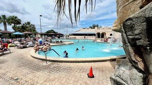 A swimming pool with people, a hexagonal tiled area, and a building with arches in the background. - 2 BR, 2 B Home.w/ Golf Cart  Located in The Villages.1 Mile from Spanish Springs (The Villages)