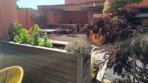 A patio area with a table and chairs, surrounded by potted plants and a wooden fence. - Studio Forêt (Amnéville)