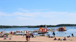A beach with a water park, including slides and inflatable structures. - Studio Forêt (Amnéville)