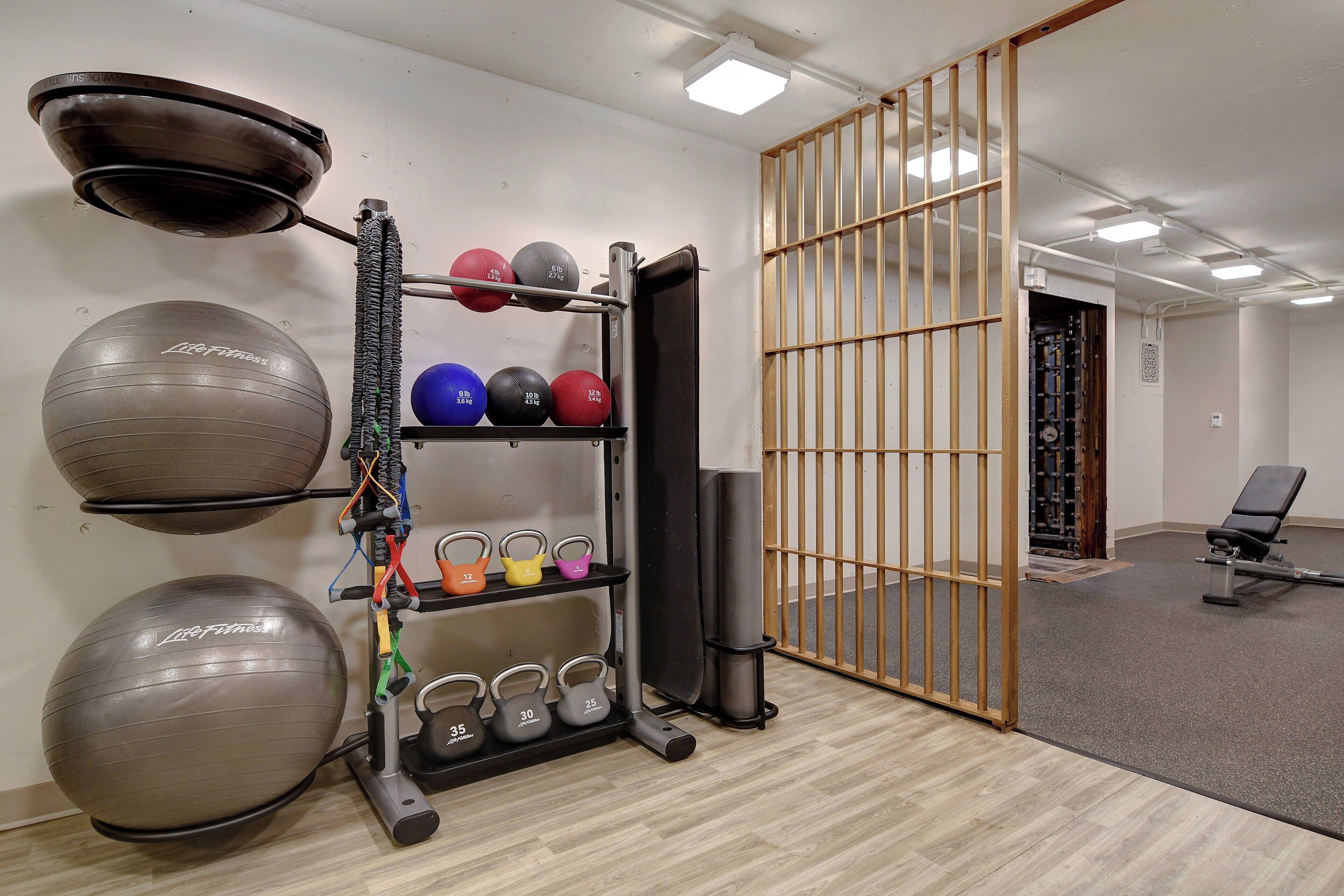 A gym with exercise balls, kettlebells, and a bench.