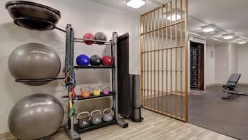 A gym with exercise balls, kettlebells, and a bench.