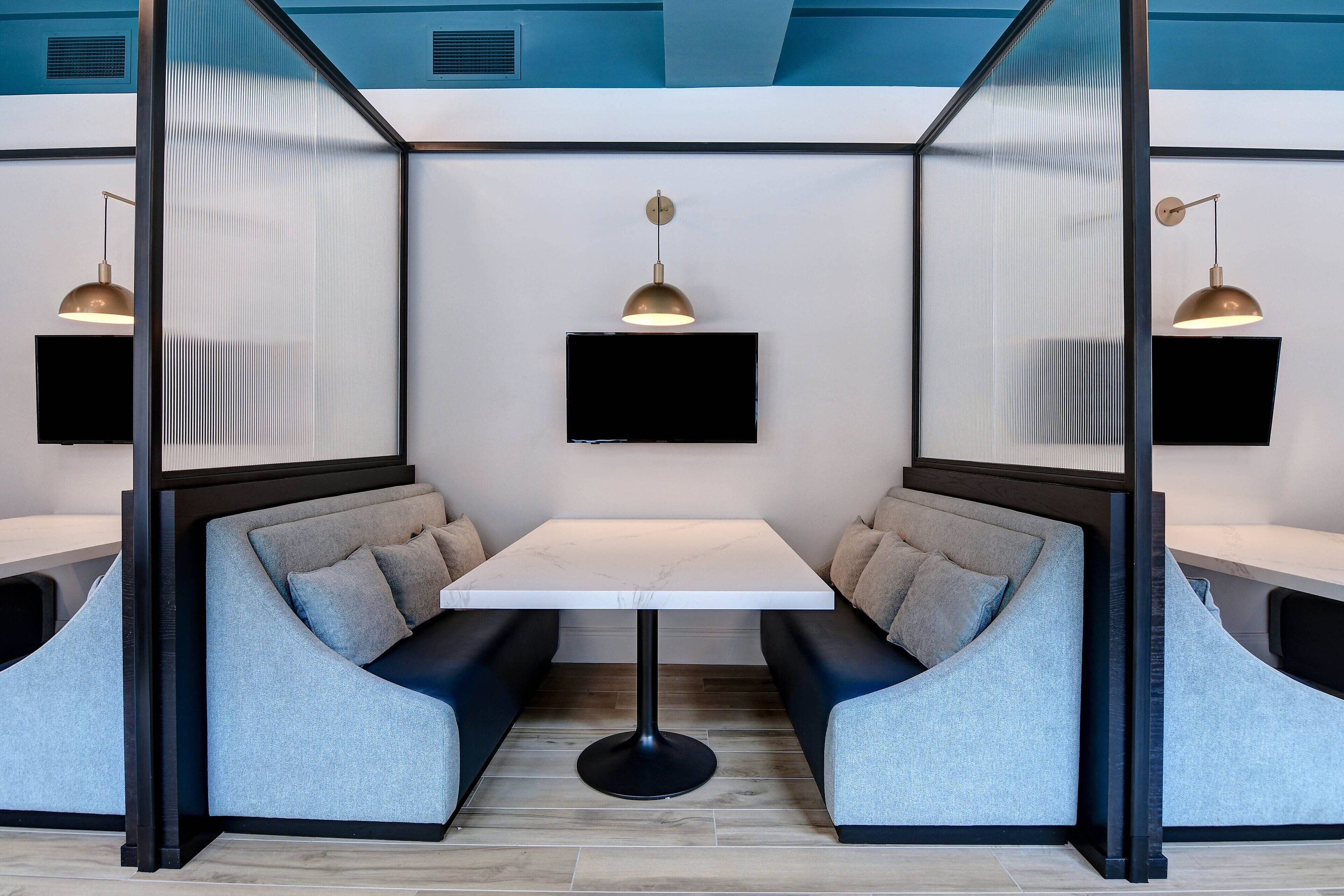 A modern room with a central table, two seating areas with cushions, and two pendant lights.