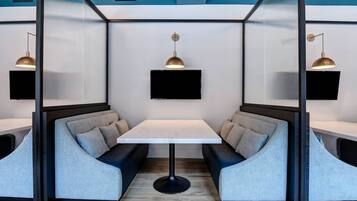 A modern room with a central table, two seating areas with cushions, and two pendant lights.