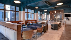 A modern lounge area with seating arrangements, a bar, and large windows providing views. - Courtyard by Marriott Cincinnati Downtown (Cincinnati)
