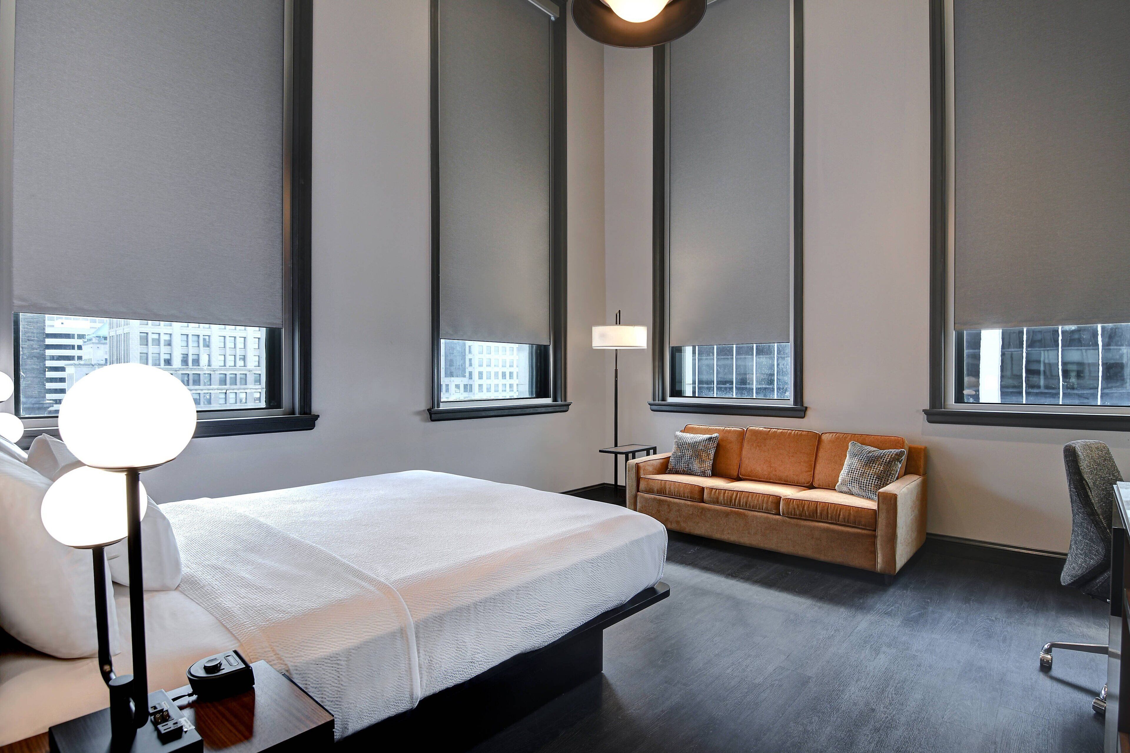 Una habitación de hotel moderna con una cama grande, un sofá, un escritorio y una lámpara.
