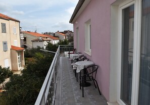 Ein Balkon mit Tischen und Stühlen mit Blick auf eine Wohngegend mit Häusern und Bäumen.
