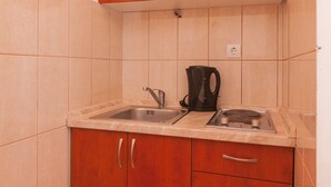 A compact kitchen with wooden cabinets, a double sink, and a coffee maker. - Apartments Island Beat - Two Bedroom Apartment with Balcony (A6) (Supetar)