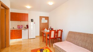 Un espacio habitable compacto con kitchenette, comedor y sofá.