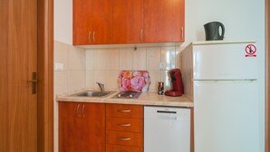 Una cocina compacta con armarios de madera, un fregadero, una cafetera y un refrigerador.