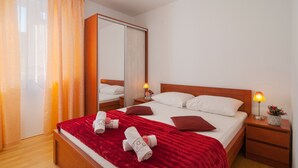 A hotel room with a bed, a nightstand, a mirror, and a window with curtains. - Apartments Island Beat - Two Bedroom Apartment with Balcony (A9) (Supetar)