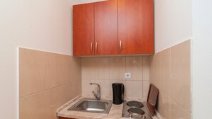 A compact kitchen with a sink, a coffee maker, and a stove. - Apartments Island Beat - Two Bedroom Apartment with Balcony (A9) (Supetar)